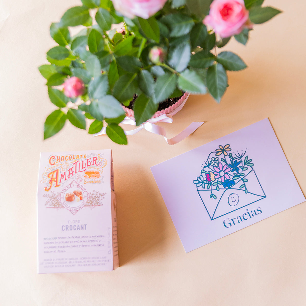 GID 71188862042485 — detalle cenital de bombones y tarjeta: Detalle bombones Amatller crocant y tarjeta Gracias floral junto a rosal pitimií rosa, regalo de agradecimiento a domicilio - Colvin

