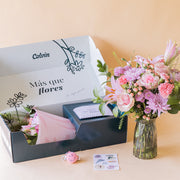 Ramo de flores pastel de Colvin en jarrón de cristal junto a caja de envío "Más que flores" con llavero smiley rosa y stickers