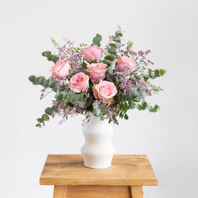 La niña le da a su mamá una caja de regalo y un ramo de flores de